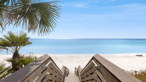 A wooden boardwalk leading to a beach with clear blue water and a palm tree. - Luxury Home w/ Private Heated Pool in Seagrove! (Santa Rosa Beach)