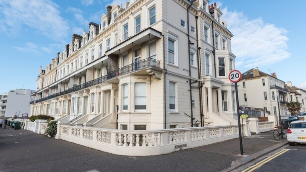 A multi-story building with a classic architectural style, featuring a prominent balcony on the second floor. - Immaculate 1-Bed Apartment on Hove Seafront (Hove)