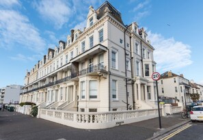 A multi-story building with a classic architectural style, featuring a prominent balcony on the second floor. - Immaculate 1-Bed Apartment on Hove Seafront (Hove)