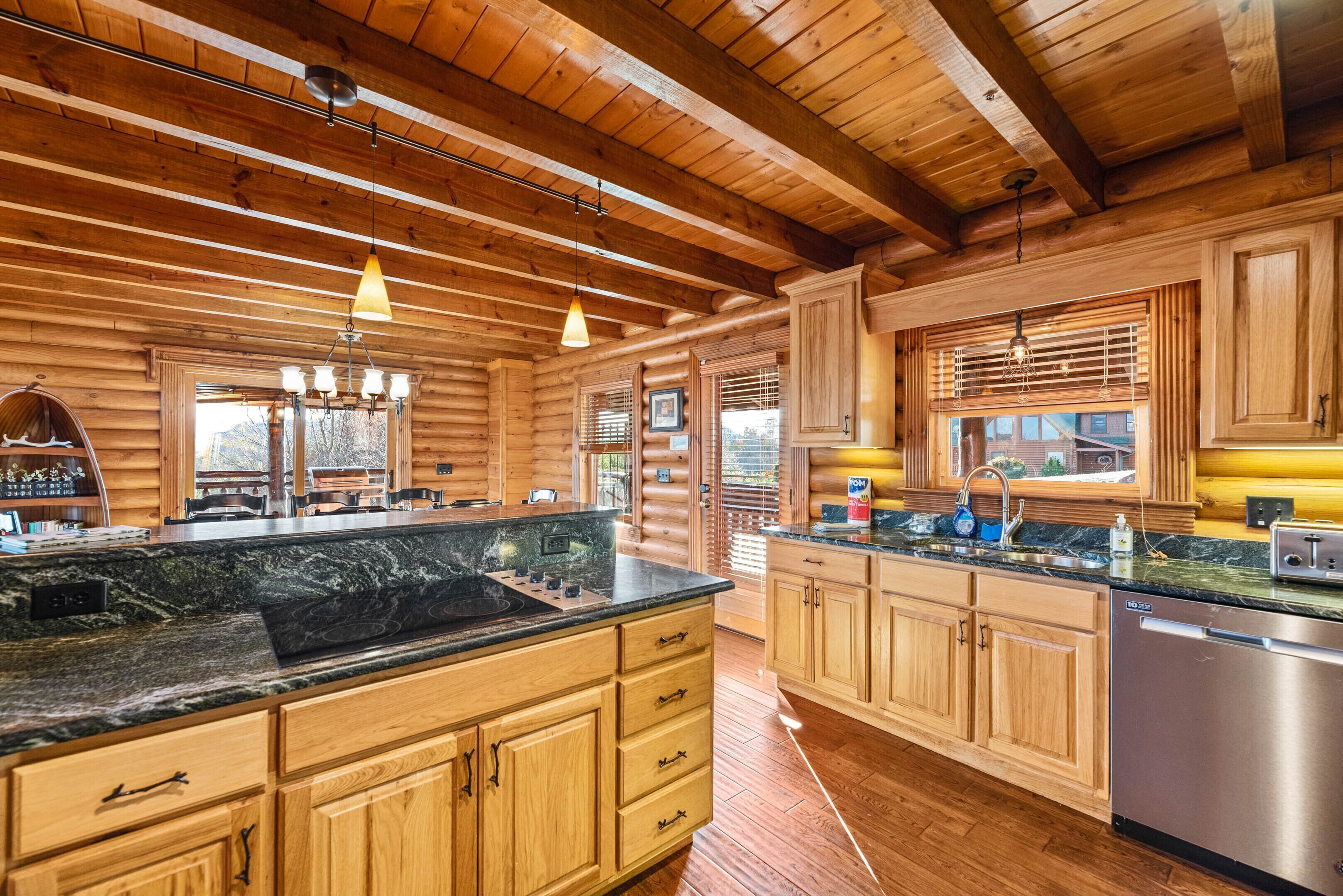 A log cabin kitchen with wooden cabinets, a granite countertop, and pendant lighting.