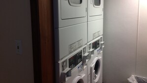 A laundry room with stacked washers and dryers, control panels, and a door. - Hotel Pratt in the heart of Cooperstown, New York **Baseball Central** (Cooperstown)