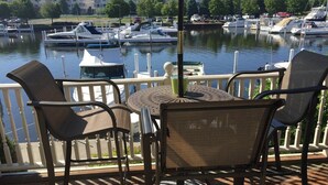 A deck with outdoor furniture overlooking a marina with boats. - Modern Condo w/ Harbor views and Community Pool (Manistee)