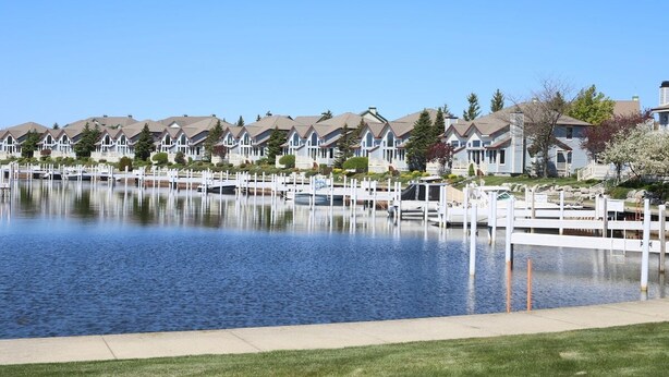 A waterfront residential area with row houses, docks, and a calm lake. - Modern Condo w/ Harbor views and Community Pool (Manistee)