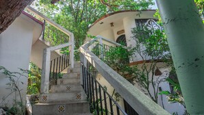 A concrete staircase with decorative tiles, surrounded by lush greenery and a white building with a curved roof. - Hotel Paraiso Encantado (Xilitla)