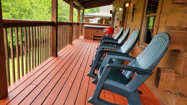 Un'area esterna con decking in legno, sedie a dondolo e un barbecue.