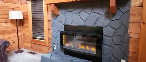 Una chimenea con revestimiento de piedra, un fuste de madera adornado con figuras de osos y una lámpara a la izquierda.