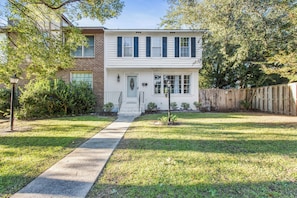 A two-story house with a front porch, a mailbox, and a small front yard. - Sweet Magnolia: Chic Haven with Fenced Backyard! (Mount Pleasant)
