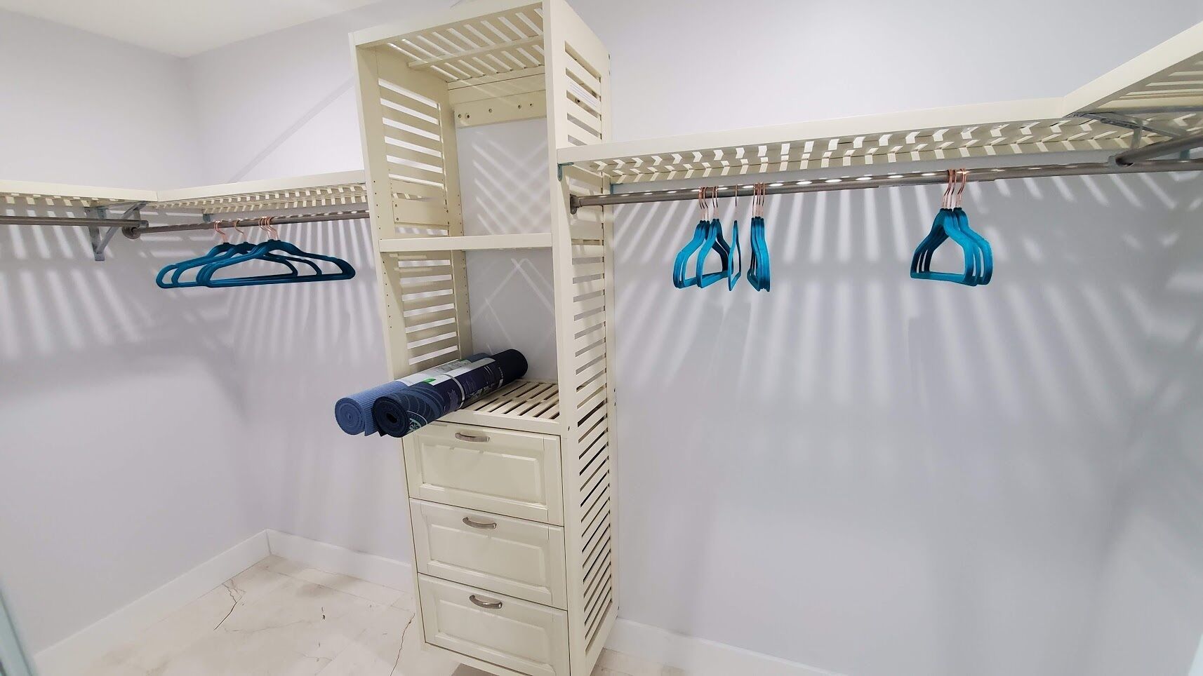 Un vestidor con estantes integrados, una barra para colgar ropa y un cajón de almacenamiento.