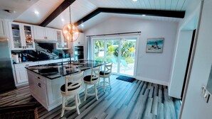 Una cocina moderna con una isla grande, armarios blancos y un salpicadero de vidrio.