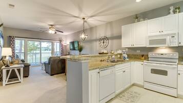 A modern kitchen with white cabinets, a granite countertop, a built-in oven, and a microwave.