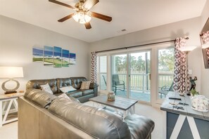 A modern living room with a leather sectional sofa, a ceiling fan, and a large sliding glass door leading to a patio. - World Tour Golf Links Condos by Escape (Myrtle Beach)