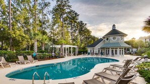 Uma área de piscina com espreguiçadeiras, um gazebo e um edifício com telhado em cúpula.