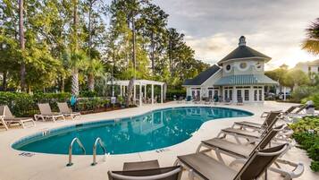 A pool area with lounge chairs, a gazebo, and a building with a dome roof.