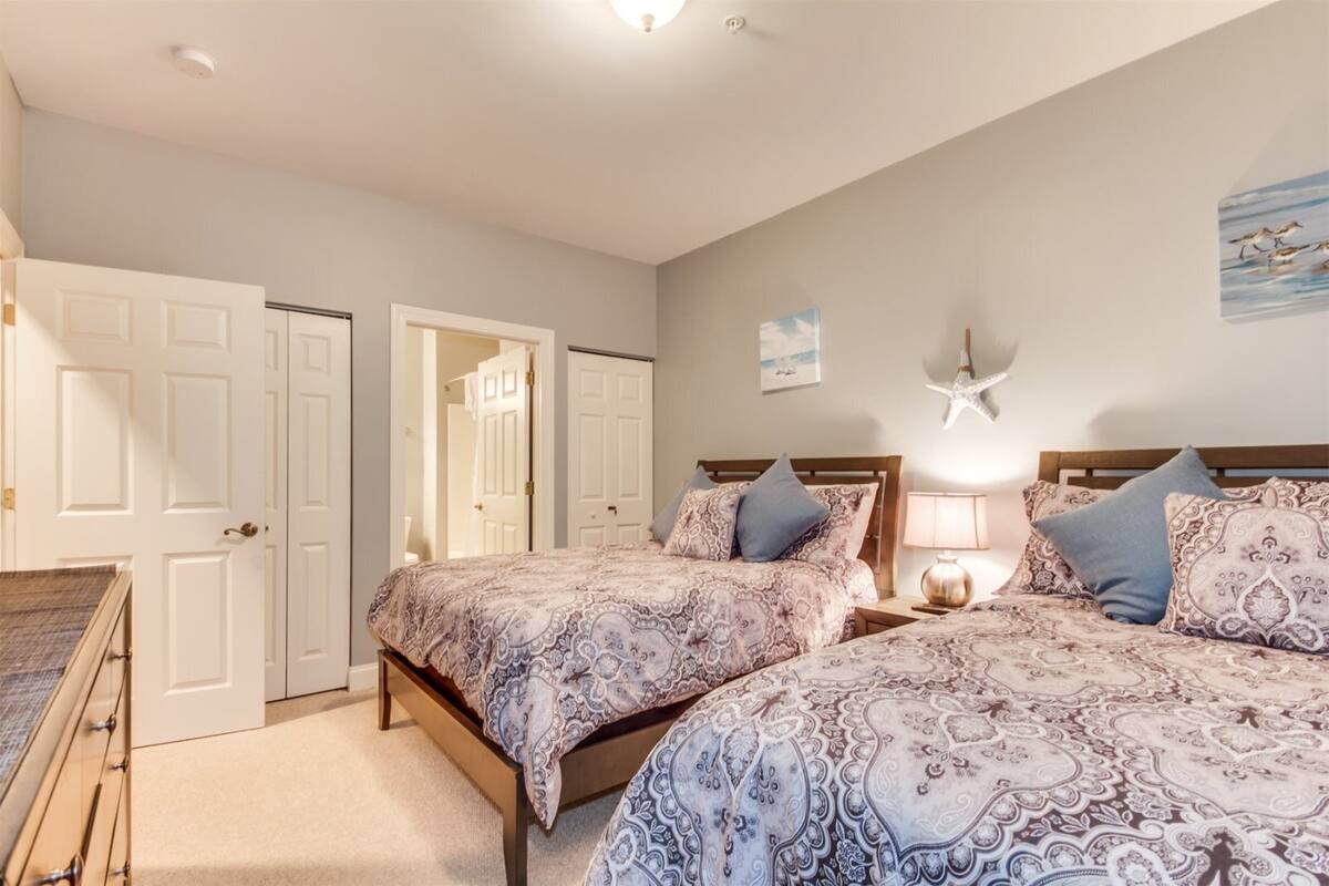 A bedroom with two beds, a nightstand, a lamp, and a starfish decoration on the wall.