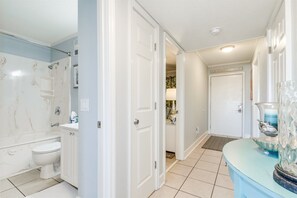 Un bany amb banyera, vàter i rentamig. Hi ha una porta que dona a una altra habitació.