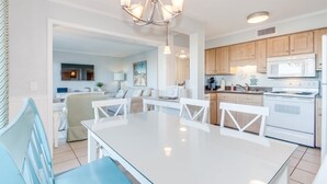 A modern kitchen with white cabinets, a central island with chairs, and a chandelier. - Myrtle Beach Resort  (Myrtle Beach)