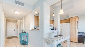A modern kitchen with white cabinets, a blue table, and a hanging light fixture. - Myrtle Beach Resort  (Myrtle Beach)