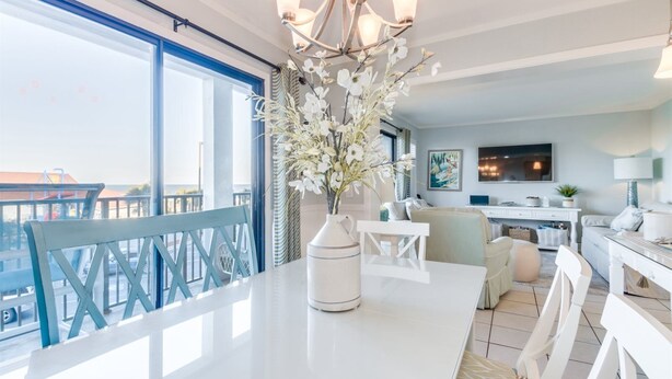 A modern living room with a large window, a white dining table, and a chandelier. - Myrtle Beach Resort  (Myrtle Beach)