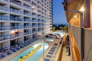 A multi-story hotel with balconies, a pool area with sun loungers, and a view of the ocean. - Forest Dunes 1501 Escape! (Myrtle Beach)