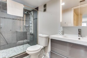 A modern bathroom with a glass-enclosed shower, a toilet, and a sink with a mirror. - Forest Dunes 1501 Escape! (Myrtle Beach)