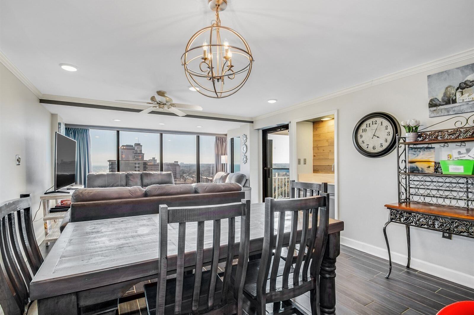 A modern living room with a dining table, sofa, and a view of the cityscape through large windows.