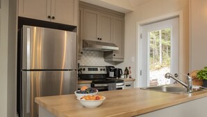 A modern kitchen with stainless steel appliances, a wooden countertop, and a view of the outdoors.