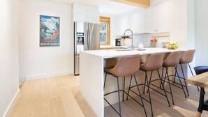 Een moderne keuken met een centraal eiland, roestvrijstalen apparatuur en barstoelen.