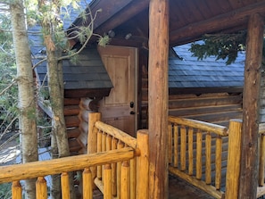 Escape to a serene retreat surrounded by trees, with a cozy cabin featuring a wooden door and staircase.