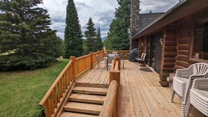 A wooden deck with outdoor furniture, a staircase, and a log cabin structure. - Sleeps 27, Dog Friendly, Fireplace, Ping Pong, Bumper Pool Table, Jetted tub (Fremont County)