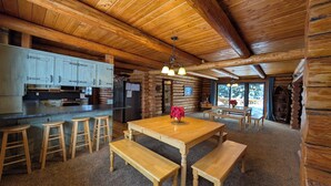 A log cabin interior with a kitchen, dining area, and a view of the outdoors. - Sleeps 27, Dog Friendly, Fireplace, Ping Pong, Bumper Pool Table, Jetted tub (Fremont County)