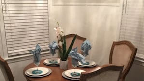 Un tavolo da pranzo con quattro sedie, un vaso con fiori e piatti con decorazioni blu.