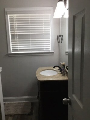 A bathroom with a window, a sink, and a door.