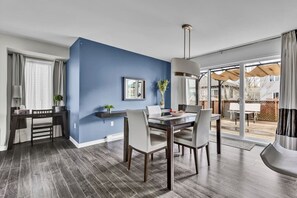 Un comedor moderno con una pared azul decorativa, una mesa de comedor con sillas y vistas al patio exterior.