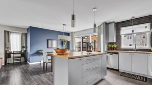 A modern kitchen with a central island, grey cabinetry, and a blue accent wall.