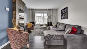 A modern living room with a grey sofa, patterned armchair, and a coffee table.
