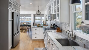 A modern kitchen with white cabinetry, a large island, and a view of the outdoors.