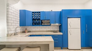 A kitchen with blue cabinets, a white refrigerator, and a marble countertop.