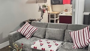 A grey sofa with striped pillows and a floral throw, a small side table, and a vase with flowers. - PROMO 5% WEEKLY DISCOUNT, ONLY FOR  NOV/ DEC /JAN /FEB.
Downtown Jasper Suite (Jasper)