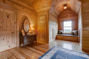 Relax in this inviting room with a wooden floor, comfortable seating area, and large window offering a view of the outdoors.