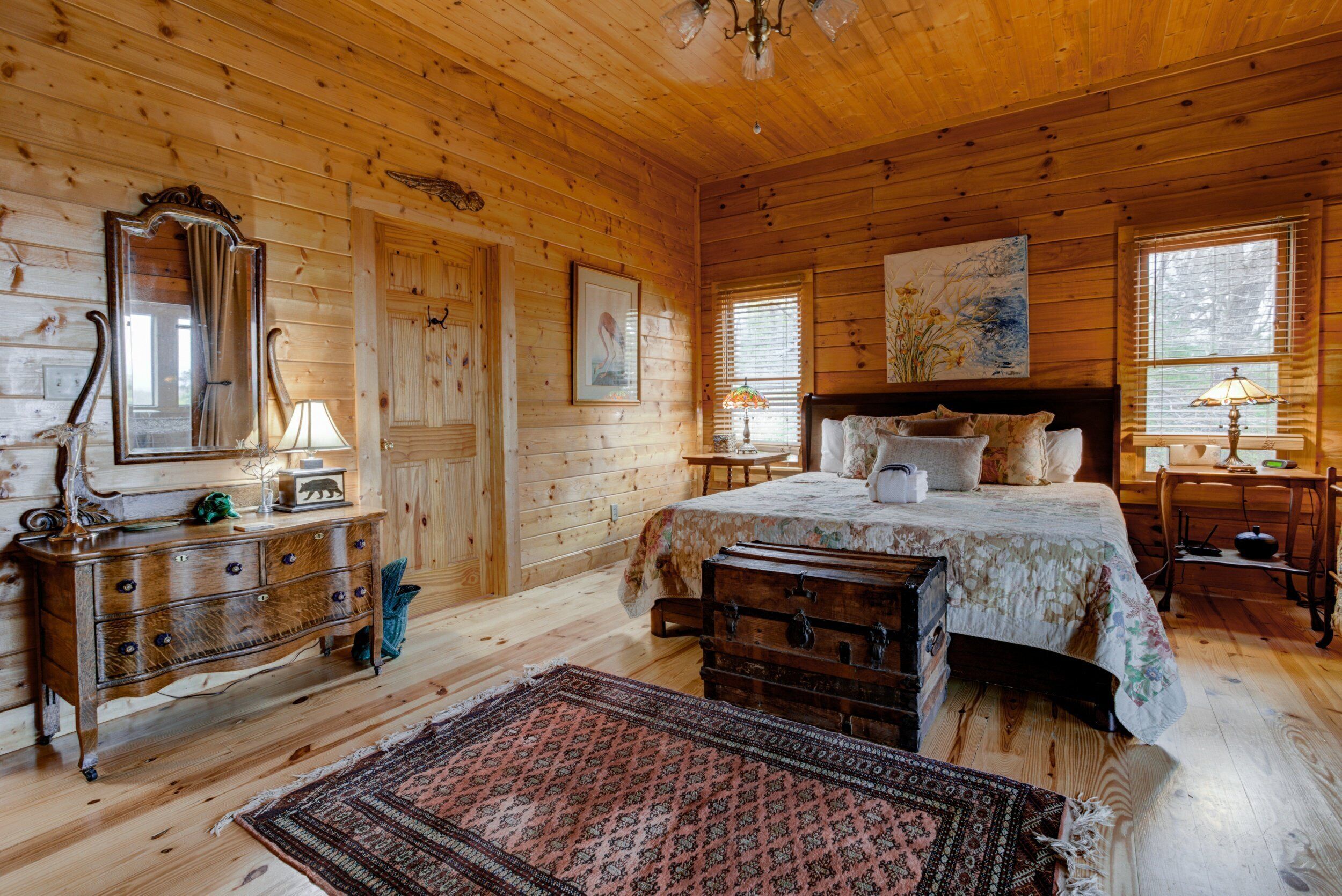 Ein Schlafzimmer einer Holzhütte mit Bett, Kommode und Schubladen.