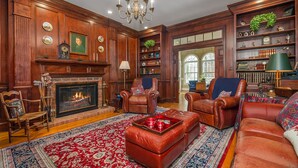 A traditional living room with a fireplace, leather furniture, and a large rug.