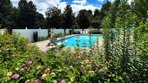 A swimming pool surrounded by lush greenery and flowering plants.