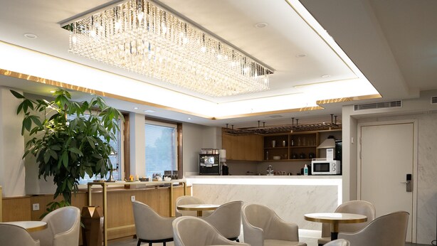 A modern restaurant with round tables and chairs, a bar area, and a kitchen in the background. - Livington Hotel (Vallingby)