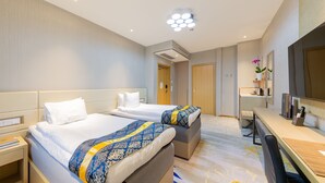 A hotel room with two beds, a desk with a chair, a TV, and a small table with a plant. - Livington Hotel (Vallingby)