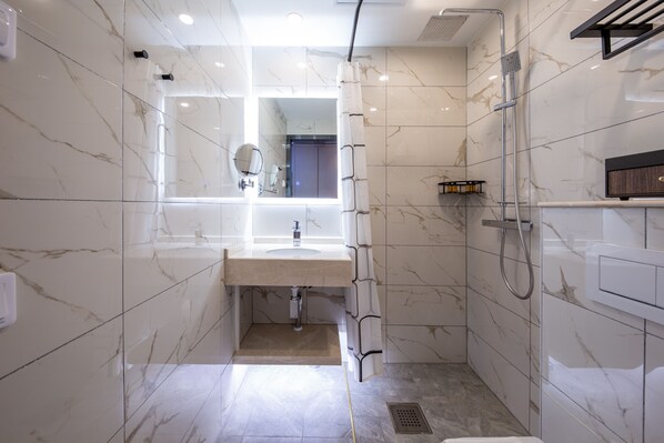 Une salle de bain moderne avec un sol en marbre, un lavabo, un miroir, une douche et des toilettes.