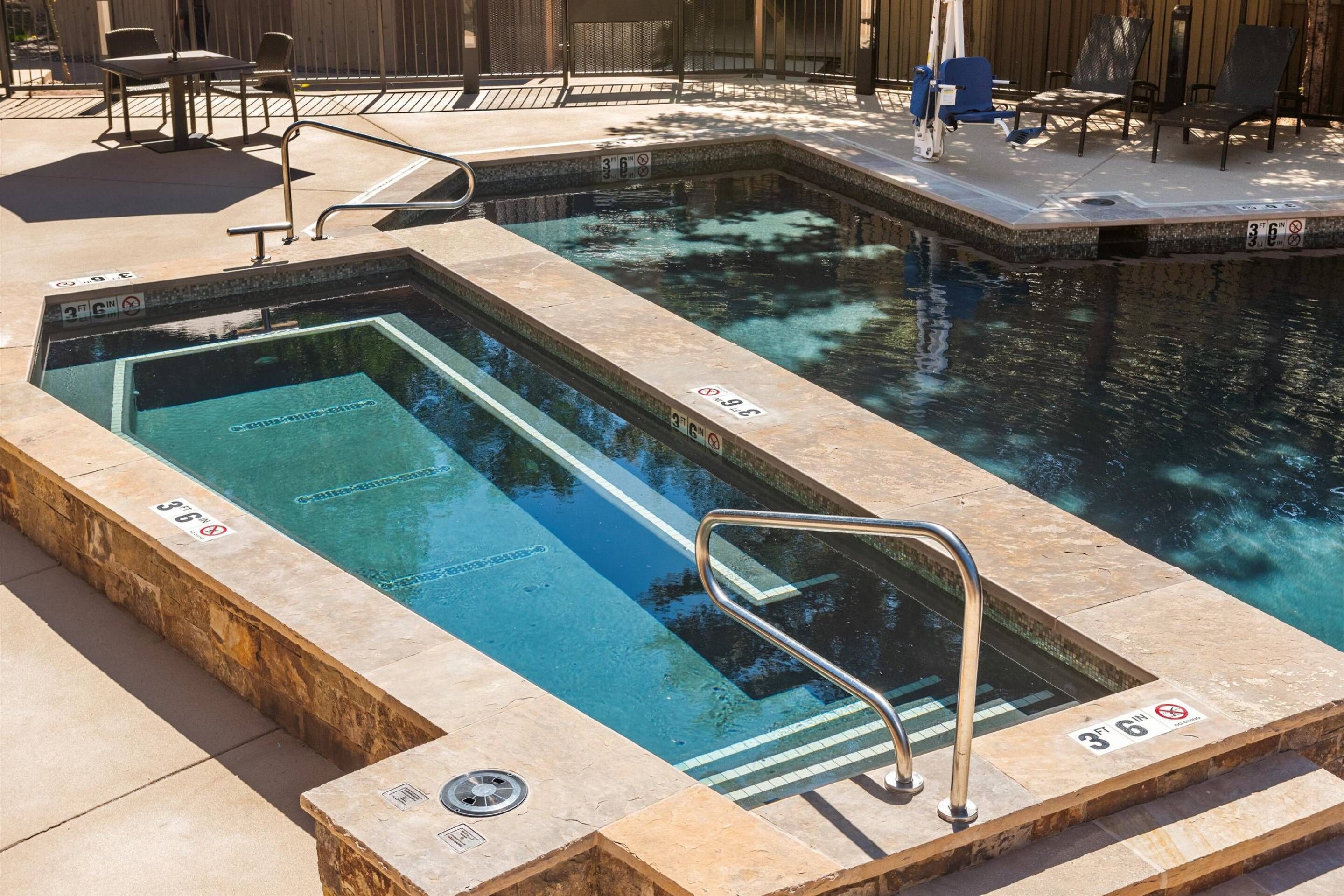 A rectangular pool with clear water, surrounded by stone steps and metal railings.