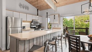 A modern kitchen with a central island, stainless steel appliances, and a view of a lush garden.