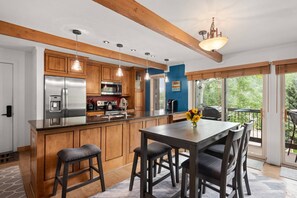 A modern kitchen with wooden cabinets, stainless steel appliances, and a large island with bar stools. - Woodbridge Condos by iTrip Aspen Snowmass (Snowmass Village)