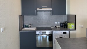 Ett kompakt kök med diskho, spis, ugn och diskmaskin.