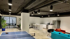 Un espace intérieur moderne comprenant une table de ping-pong, un coin cuisine et un espace détente avec un canapé.